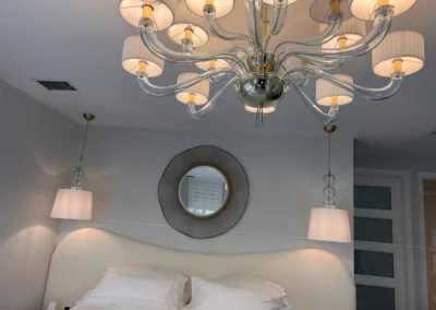A bedroom with a white bed and a chandelier.