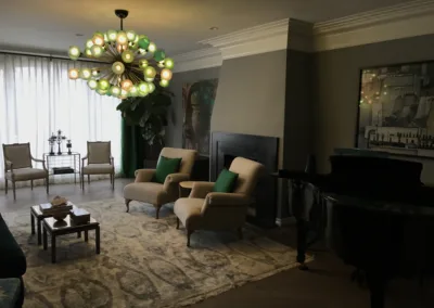 A living room with a piano, chairs and a chandelier.