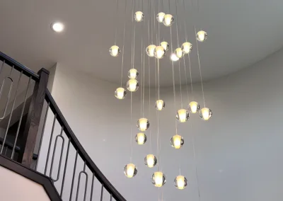 A modern staircase with a chandelier hanging above it.